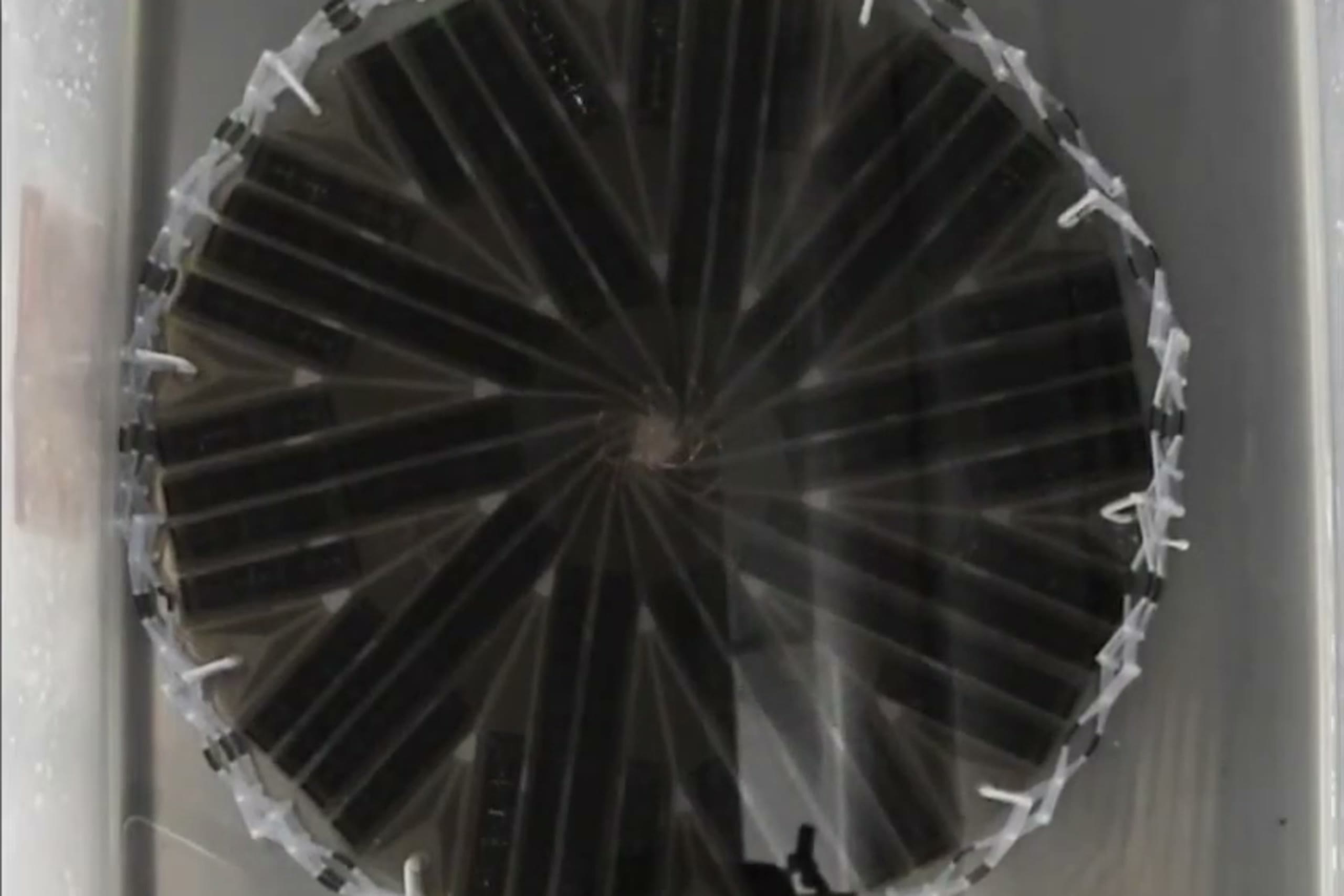 The 3D-printed origami solar array fully expanded in a water bath, flexible solar panels arranged in a spiral over the flasher origami substrate