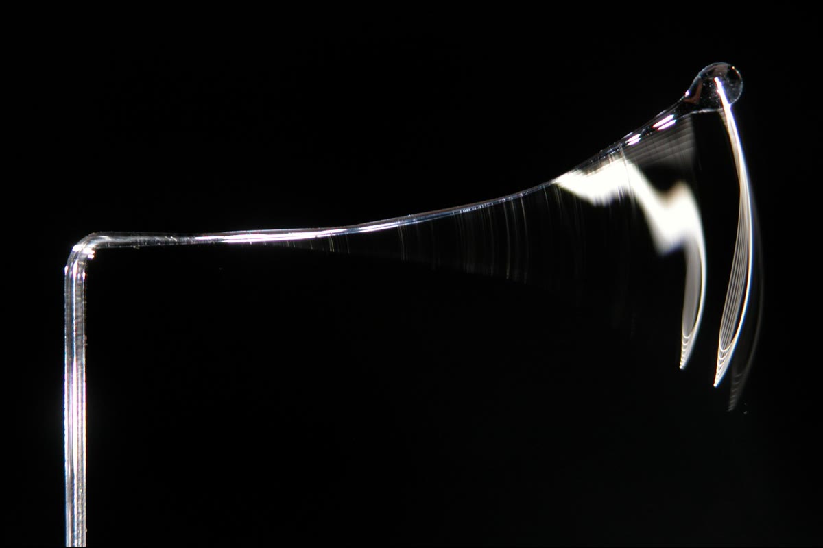 A slender elastic rod whipping back after release, photographed in a long exposure